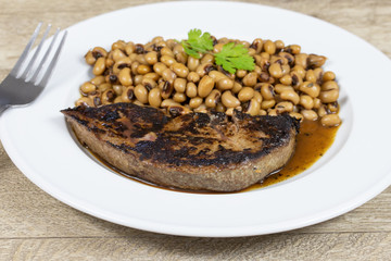 foie de veau grillé  et haricot oeil noir cuit dans une assiette