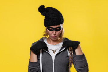 The concept of theft. A blonde woman in a hat, mask and gloves holds the jewels in both hands and...