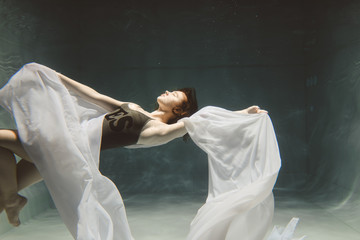 Beautiful girl swims underwater with long hair. Blue or gold background like gold. The atmosphere...