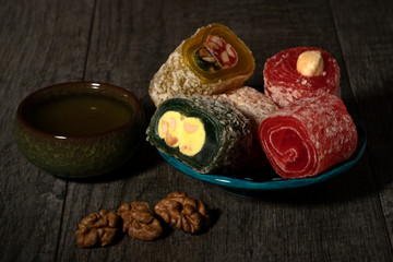 Fototapeta na wymiar Still life with pieces of Turkish delight, green tea and walnut on a old wood background