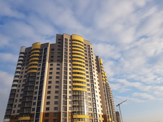 Fototapeta premium Close-up of luxury high apartment complex. Fragment of modern residential flat exterior. Blue sky with clouds. Real estate property and posh architecture concept