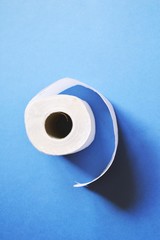 White toilet paper roll on a blue background. Deficiency during the coronavirus epidemic