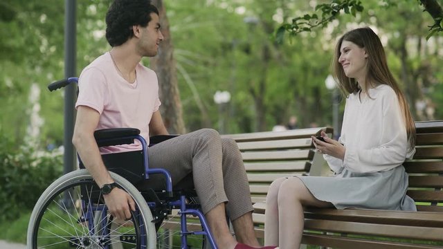 Young man in a wheelchair and woman meets in park