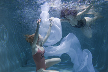 Two beautiful lesbian girls are swimming underwater. Attractiveness. Sexual poses and gestures....