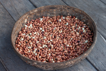 Roasted peanuts in bamboo weaving basket on wooden table background.