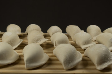 Raw dumplings, pierogi or pyrohy, varenyky, vareniki, served with cottage cheese on board. National Russian cuisine, natural organic homemade bakery product, view from above.