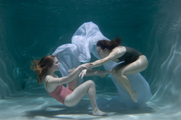 Two beautiful lesbian girls are swimming underwater. Attractiveness. Sexual poses and gestures....