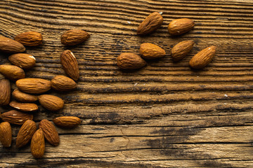 Almonds scattered on the wooden vintage table. Copy space. Almond is a healthy vegetarian protein nutritious food. Almonds on rustic old wood.