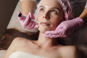 Beautiful girl on rejuvenation procedure in beauty clinic filler injection.