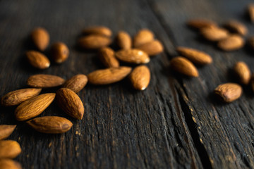 Almonds scattered on the wooden vintage table. Almond is a healthy vegetarian protein nutritious food. Almonds on rustic old wood.