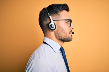 Young business operator man wearing customer service headset from call center looking to side,...