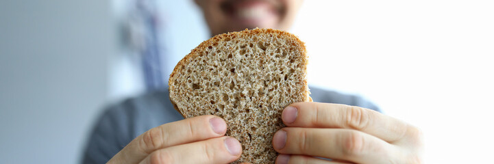 Close up happy guy holds piece whole grain bread