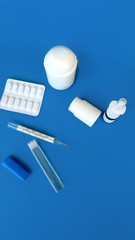 medicine  pills and white bottle, thermometer on blue background. Copy space for text stock photo           
