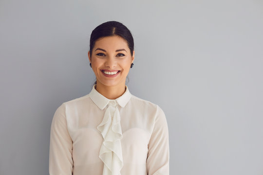 Young woman in white shirt smiling laughs joyful happy positive on a gray background.