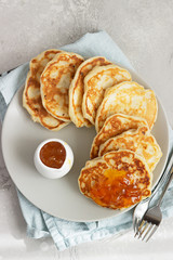 American pancakes or fritters with orange jam on ceramic plate. Light grey stone background. Breakfast. Top view.