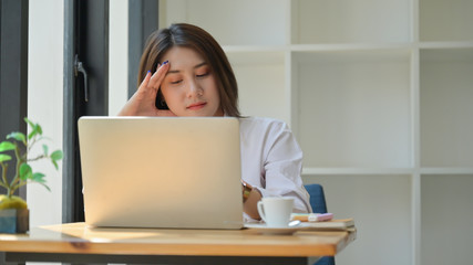A young woman uses a laptop for work,She works from home and is tired.