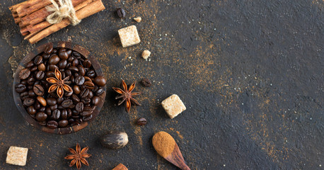 Aromatic set of coffee beans, anise stars, cinnamon sticks, brown sugar cubes and nutmeg on dark brown concrete background. Spices for Christmas cakes or drinks.