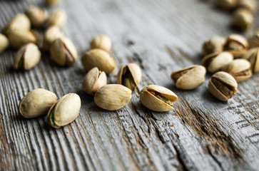 Pistachios scattered on the wooden vintage table. Pistachio is a healthy vegetarian protein nutritious food. Pistachios on rustic old wood.