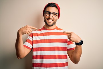 Young handsome man wearing casual striped t-shirt and glasses over white background looking...