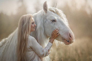 Beautiful young woman with white tinker cob in an autumn field