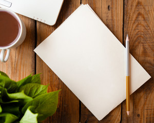 wooden table with smartphone with blank screen mockup, laptop computer, cup of coffee and supplies. Top view with copy space, flat lay.