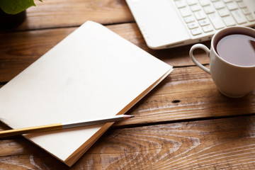 wooden table with smartphone with blank screen mockup, laptop computer, cup of coffee and supplies. Top view with copy space, flat lay.
