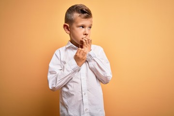Young little caucasian kid with blue eyes wearing elegant white shirt over yellow background...
