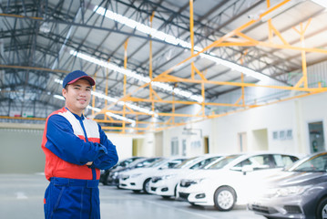 Asian car mechanic, smiling and happy, car repair service center, blurred background, blurred background for the industry