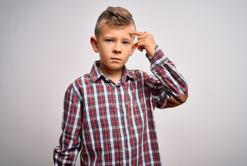 Young little caucasian kid with blue eyes wearing elegant shirt standing over isolated background pointing unhappy to pimple on forehead, ugly infection of blackhead. Acne and skin problem