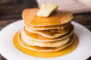 Small pancakes with maple syrup and butter on wooden table. Breakfast concept.