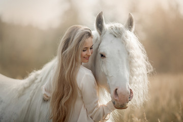 Beautiful young woman with white tinker cob in an autumn field - 345651605