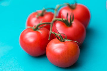 Close-up of fresh ripe cherry tomatoes on turquoise wooden background.