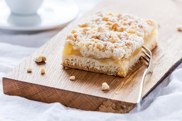 Apfelstreuselkuchen serviert auf einem rustikalen Eichebrett im Gegenlicht.