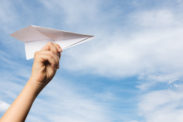 Paper airplane in hand on a blue sky.