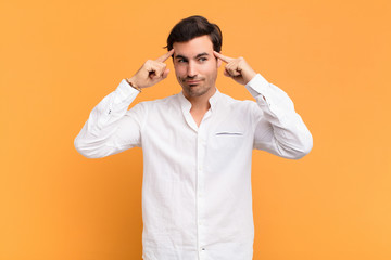 young handsome man looking concentrated and thinking hard on an idea, imagining a solution to a...