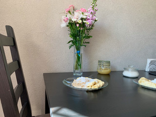 Oatmeal with coconut shavings and a banana on a black table in a glass plate. Delicious healthy Breakfast for two. A bouquet of flowers in soft pink and white tones. Breakfast for mom.