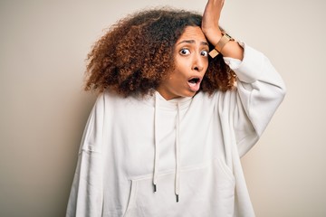 Young african american sportswoman with afro hair wearing sporty sweatshirt surprised with hand on...