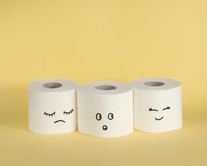 Toilet paper with sad, happy, confused face on beige background.