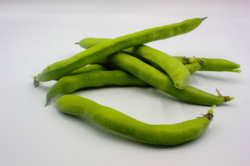 pile of fresh green broad beans in their shells isolated on a white background