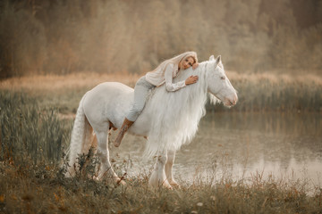Beautiful young woman with white tinker cob in an autumn field