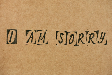 Words I am Sorry made by black alphabet stamps on Cardboard.