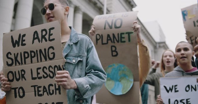 Group of students on the streets demonstrating against climate change. People protesting for problem in ecology, environment, global warming, industrial influence, climate emergency.
