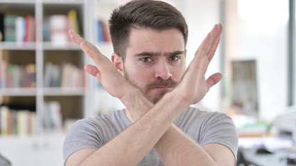 Portrait of Young Man rejecting with Arm Gesture