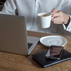 a man working at a desk and drinking coffee