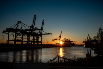Fototapeta na wymiar Container Kräne bei Sonnenuntergang