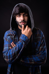 Portrait of young handsome bearded Indian hipster man with hooded shirt