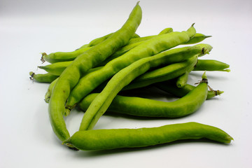 pile of fresh green broad beans in their shells isolated on a white background