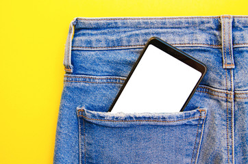 White screen smartphone in jeans pocket. Smartphone place for text. Smartphone in a pocket on a yellow background.  Copy Space