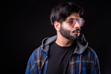 Portrait of young handsome bearded Indian hipster man with sunglasses