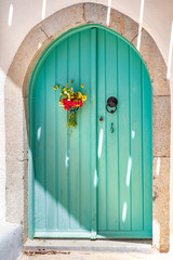 A nice traditional door of an old stone house with a bouquet of flowers, in Milatos, Crete, Greece.